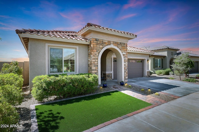 mediterranean / spanish-style home with a yard and a garage