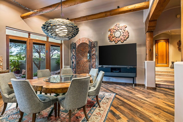 dining area featuring beam ceiling, a high ceiling, an inviting chandelier, decorative columns, and hardwood / wood-style floors