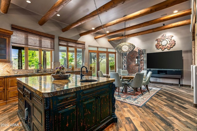 kitchen featuring backsplash, a kitchen island with sink, sink, stone countertops, and dark hardwood / wood-style flooring