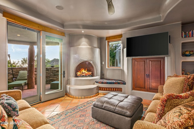 living room featuring a fireplace, a raised ceiling, and light tile patterned flooring