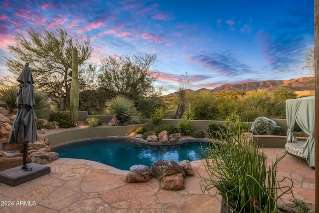 pool at dusk featuring a mountain view and a patio