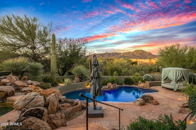 pool at dusk with a mountain view and a patio area