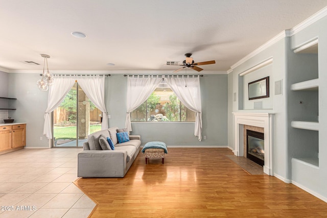 tiled living room featuring a tiled fireplace, a wealth of natural light, and ornamental molding