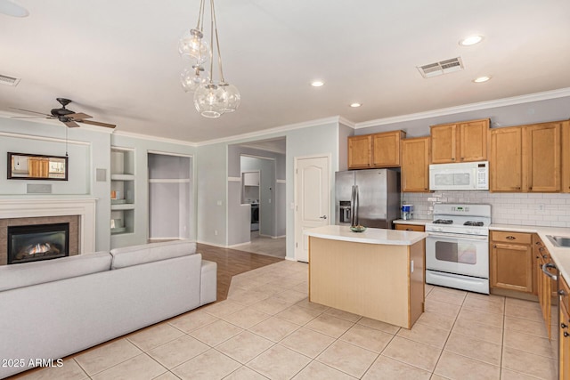 kitchen featuring decorative light fixtures, a center island, light tile patterned floors, ornamental molding, and white appliances