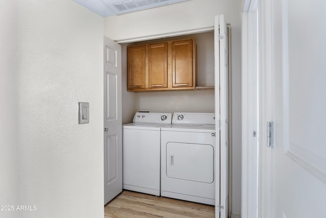 washroom with washer and clothes dryer, cabinets, and light wood-type flooring