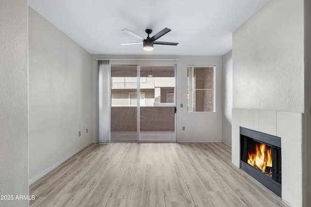 unfurnished living room featuring a fireplace, light hardwood / wood-style floors, and ceiling fan