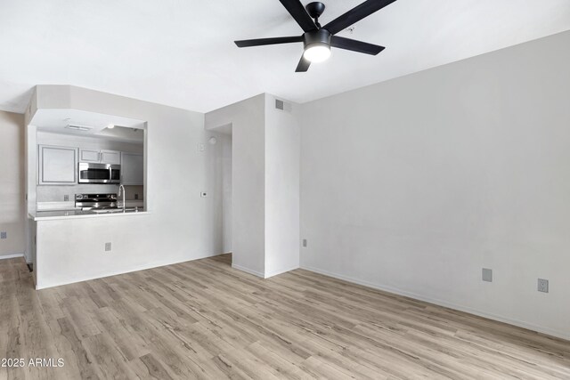 unfurnished living room featuring ceiling fan, light hardwood / wood-style flooring, and sink