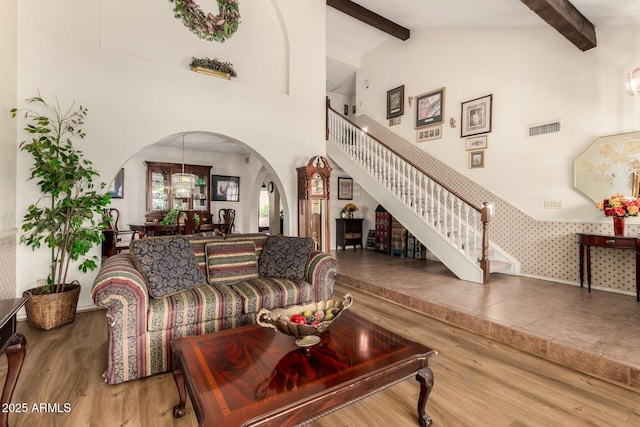 4601 E Sunnyside Ln, Phoenix, AZ 85032 - living area featuring arched walkways, stairs, wood finished floors, beam ceiling, and high vaulted ceiling