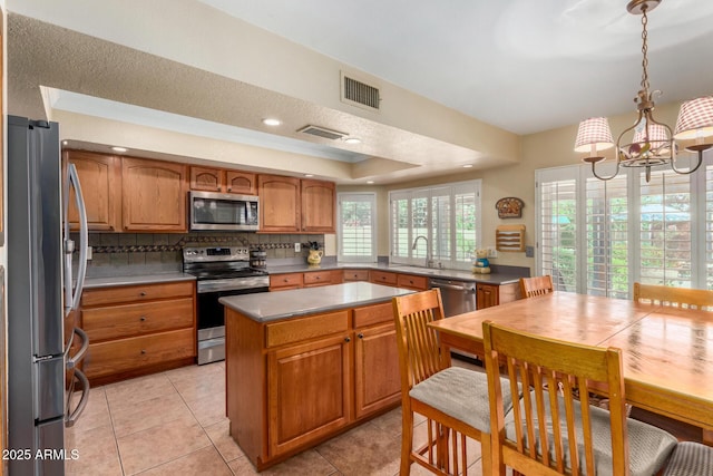 4601 E Sunnyside Ln, Phoenix, AZ 85032 - kitchen with appliances with stainless steel finishes, a sink, brown cabinetry, a chandelier, and a raised ceiling
