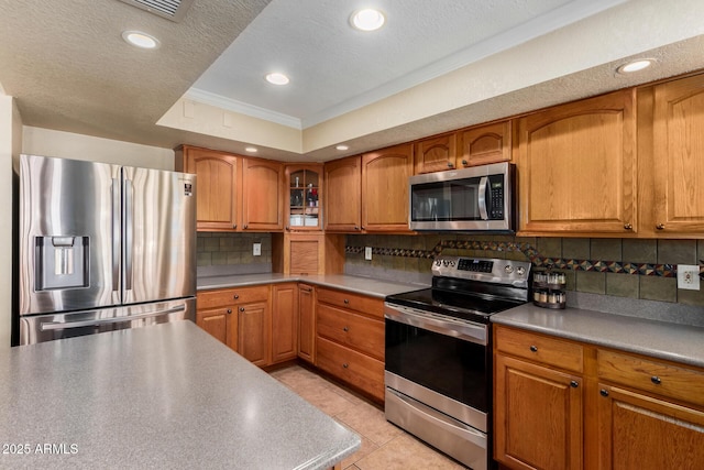 4601 E Sunnyside Ln, Phoenix, AZ 85032 - kitchen featuring stainless steel appliances, crown molding, brown cabinets, a raised ceiling, and decorative backsplash