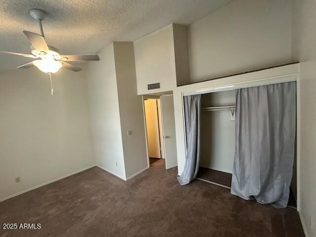 unfurnished bedroom featuring baseboards, a textured ceiling, dark carpet, visible vents, and a closet