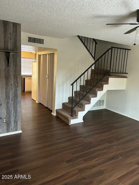 stairway featuring a textured ceiling, visible vents, a ceiling fan, and wood finished floors