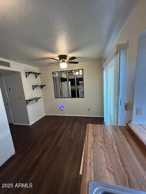 unfurnished living room featuring visible vents, a textured ceiling, wood finished floors, and a ceiling fan