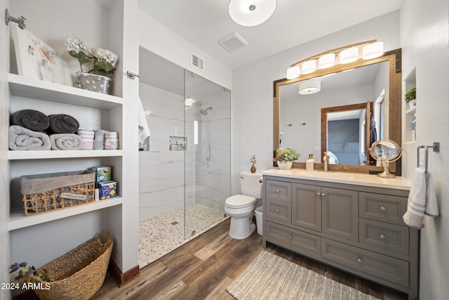 bathroom with vanity, wood finished floors, visible vents, a marble finish shower, and toilet