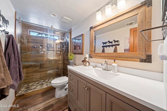 full bath featuring visible vents, toilet, wood finished floors, a shower stall, and vanity