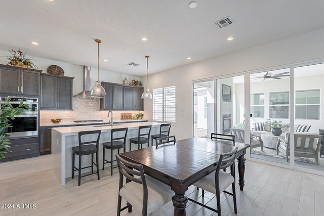 dining area with ceiling fan, light hardwood / wood-style flooring, and sink