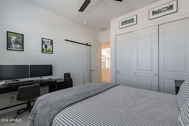 carpeted bedroom with a barn door and ceiling fan