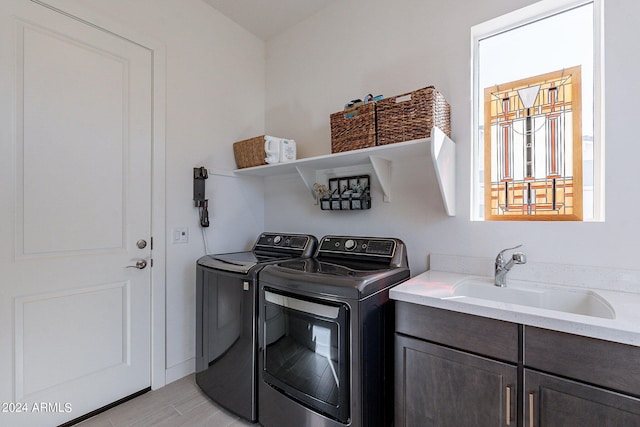 clothes washing area featuring cabinets, light hardwood / wood-style floors, sink, and washing machine and clothes dryer