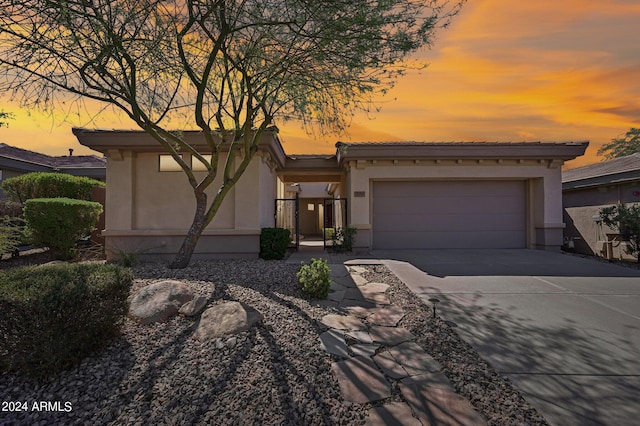 view of front of house featuring a garage, a gate, driveway, and stucco siding