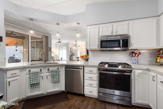 kitchen with dark wood finished floors, decorative backsplash, stainless steel appliances, white cabinetry, and a sink