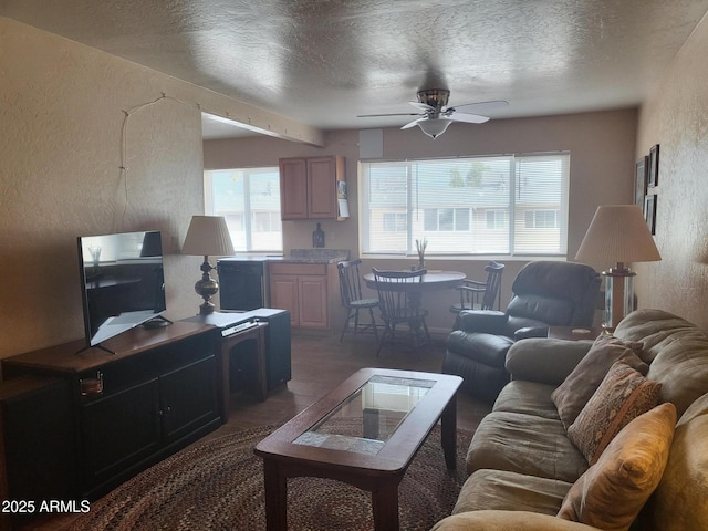 living room featuring ceiling fan and a textured ceiling