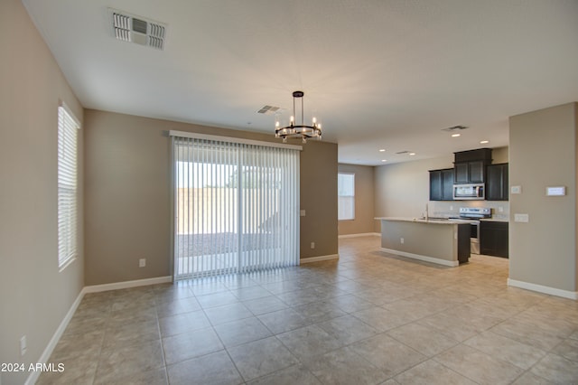 unfurnished living room featuring a notable chandelier and light tile patterned floors