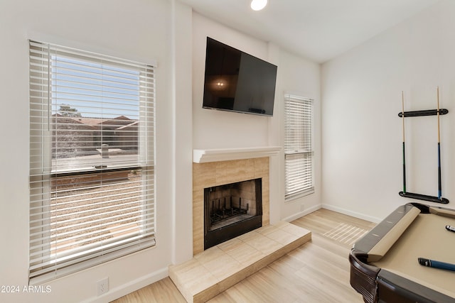 living room featuring a tiled fireplace, a wealth of natural light, and light hardwood / wood-style flooring