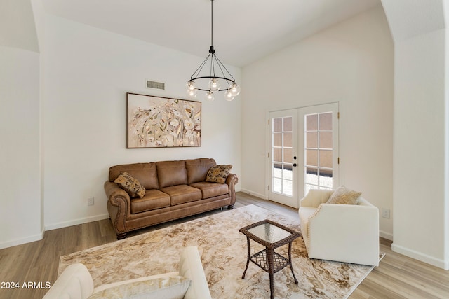 living room with light wood-type flooring, a chandelier, french doors, and lofted ceiling