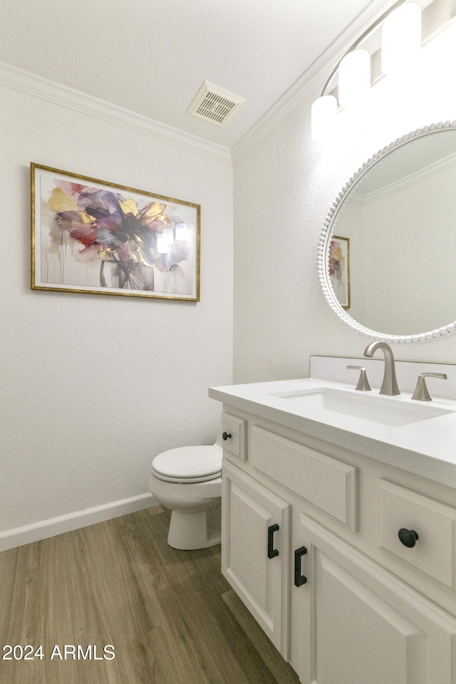 bathroom featuring toilet, vanity, hardwood / wood-style flooring, and ornamental molding