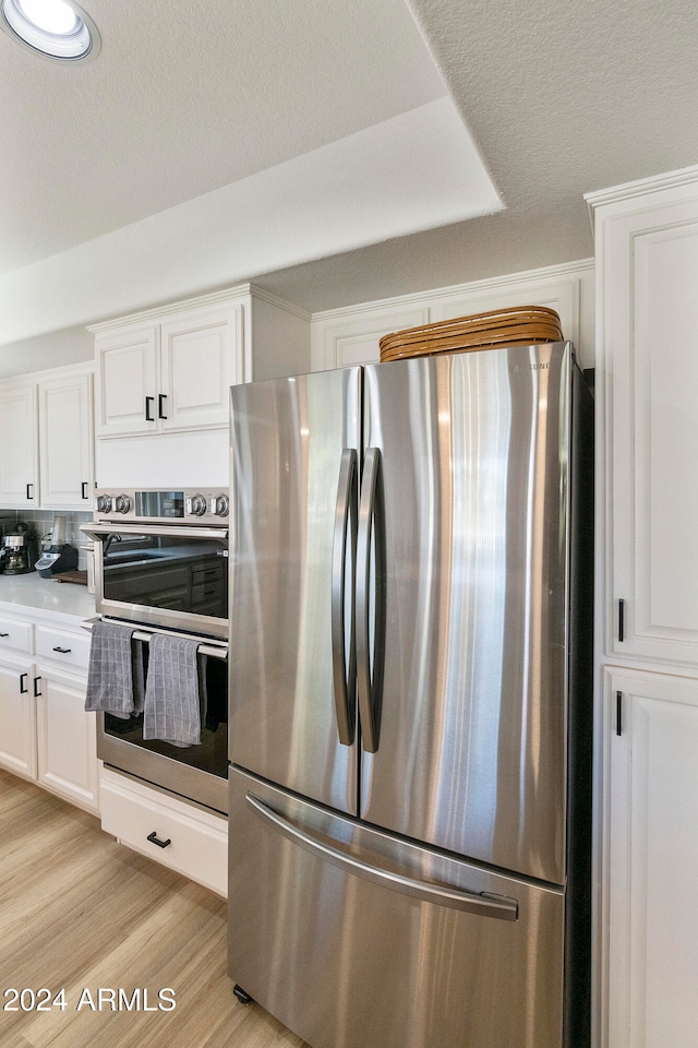 kitchen featuring white cabinets, light wood-type flooring, and appliances with stainless steel finishes