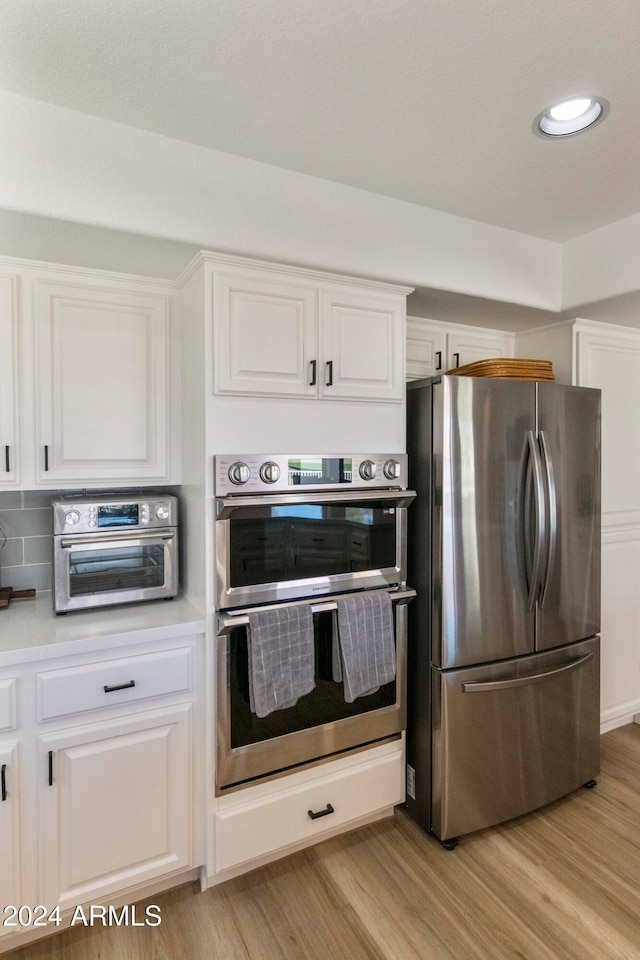 kitchen featuring white cabinets, light wood-type flooring, and appliances with stainless steel finishes