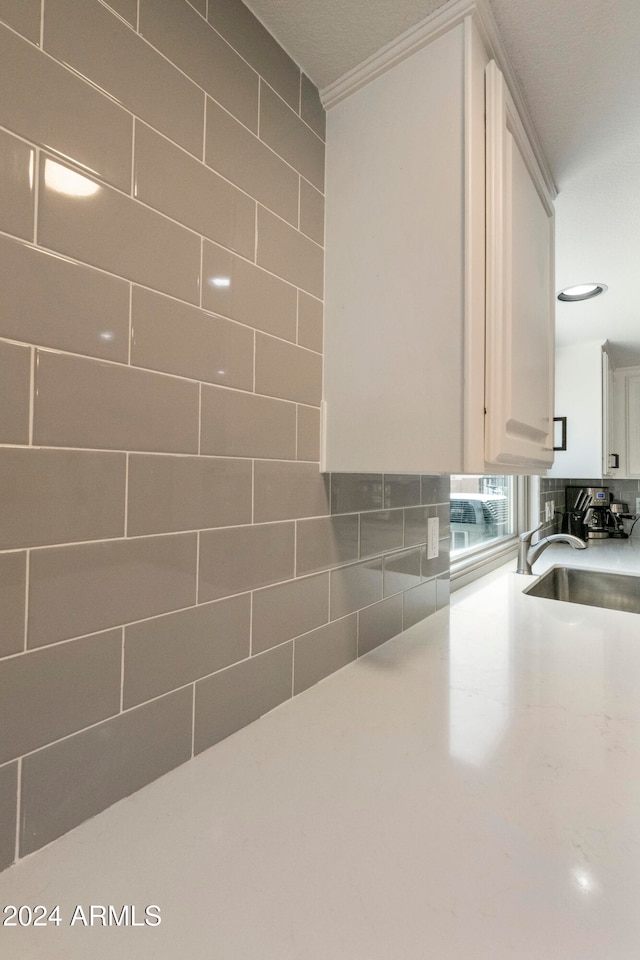 kitchen with white cabinetry, sink, and ornamental molding