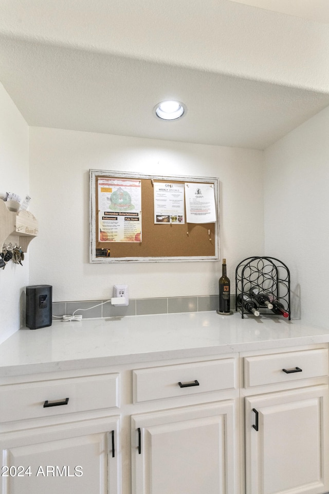 bar featuring white cabinetry and light stone countertops