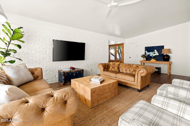 living room with hardwood / wood-style flooring, ceiling fan, and brick wall