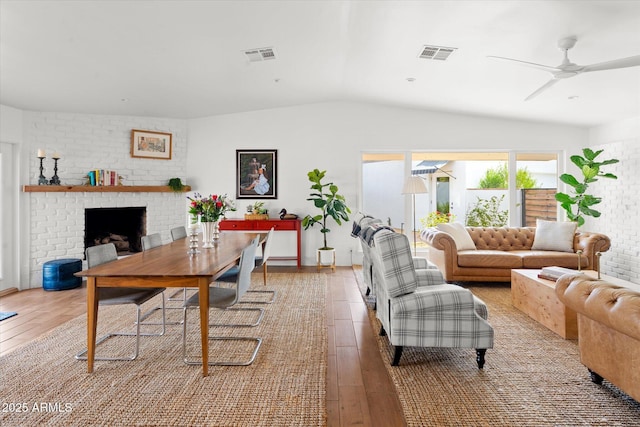 living room featuring hardwood / wood-style flooring, ceiling fan, lofted ceiling, and a fireplace