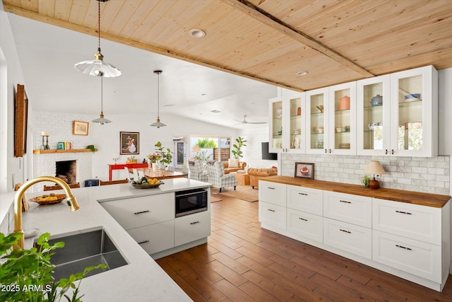 kitchen featuring a fireplace, wood counters, decorative light fixtures, black microwave, and sink