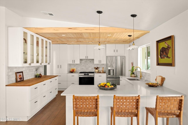 kitchen with a kitchen bar, sink, hanging light fixtures, stainless steel appliances, and white cabinets