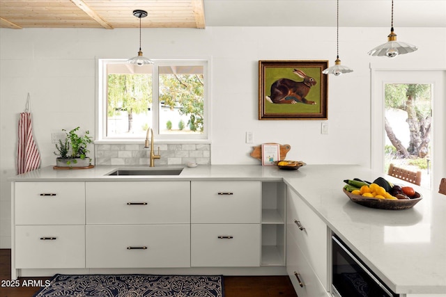 kitchen with white cabinetry, sink, wood ceiling, and decorative light fixtures