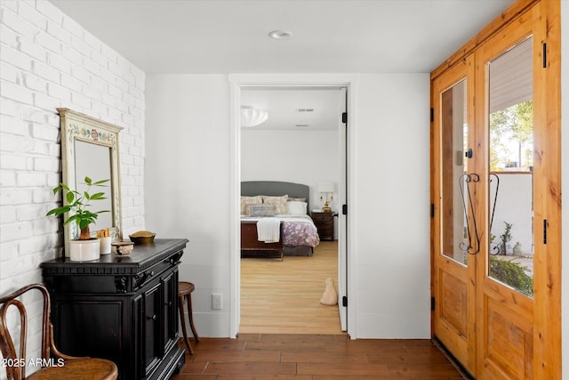 bedroom featuring brick wall and dark hardwood / wood-style floors