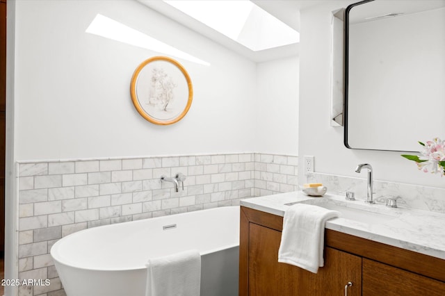 bathroom featuring vanity, a bathing tub, a skylight, and tile walls