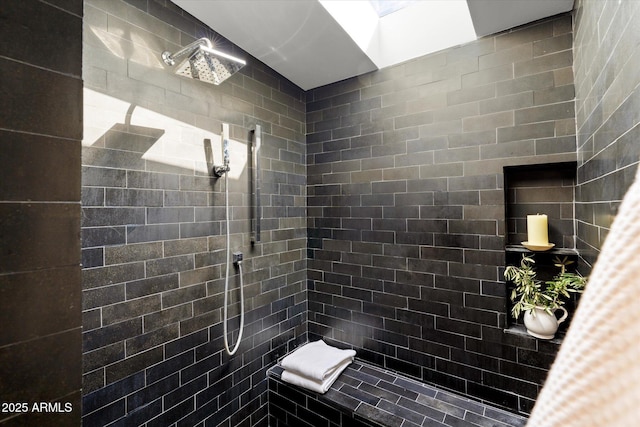 bathroom with tiled shower and a skylight