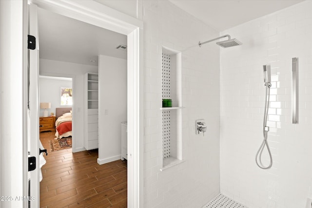 bathroom with wood-type flooring and a tile shower