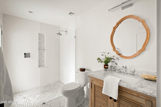 bathroom featuring vanity, toilet, and a tile shower