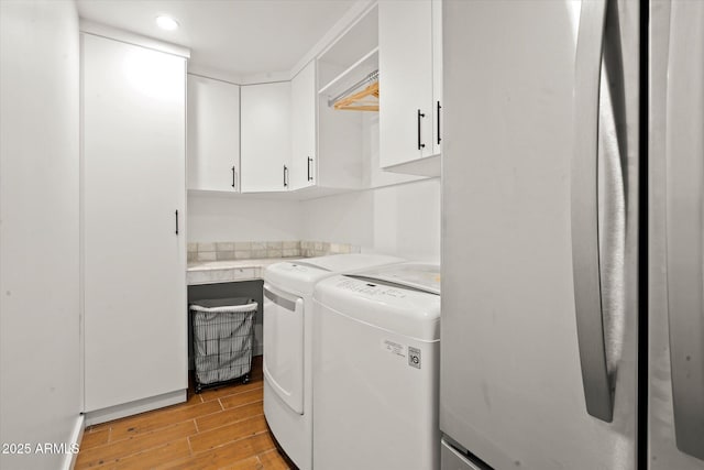 clothes washing area with separate washer and dryer and cabinets