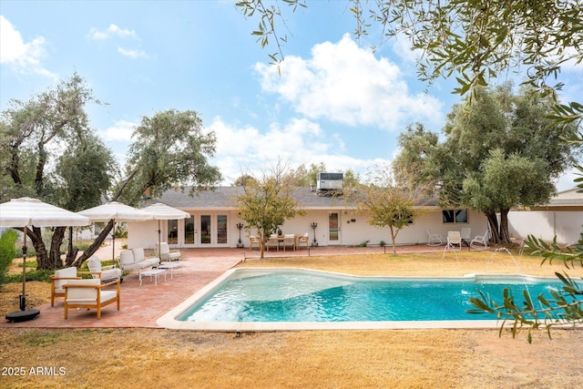 view of pool featuring an AC wall unit, a yard, and a patio area