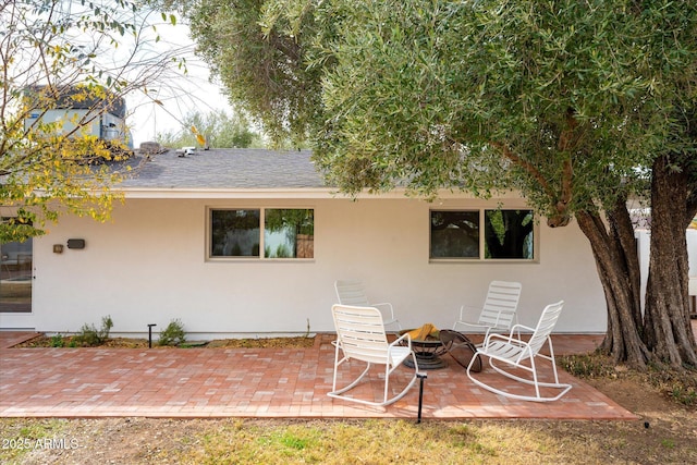 back of property featuring a fire pit and a patio area