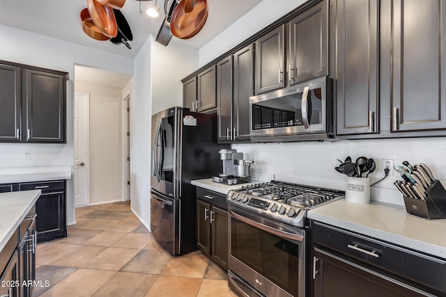 kitchen featuring light tile patterned flooring, stainless steel appliances, light stone counters, and dark brown cabinetry