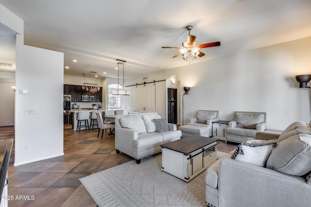 living room with ceiling fan and a barn door