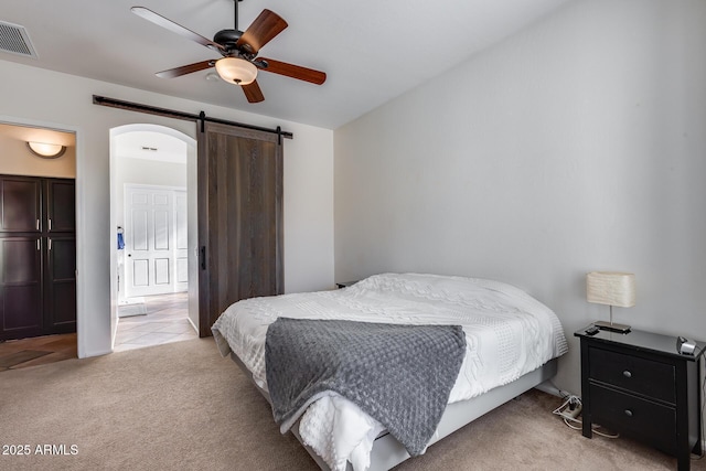 carpeted bedroom featuring ceiling fan and a barn door