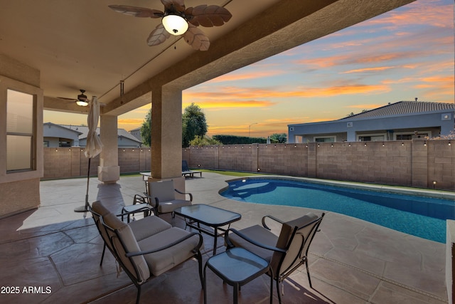 pool at dusk featuring ceiling fan and a patio